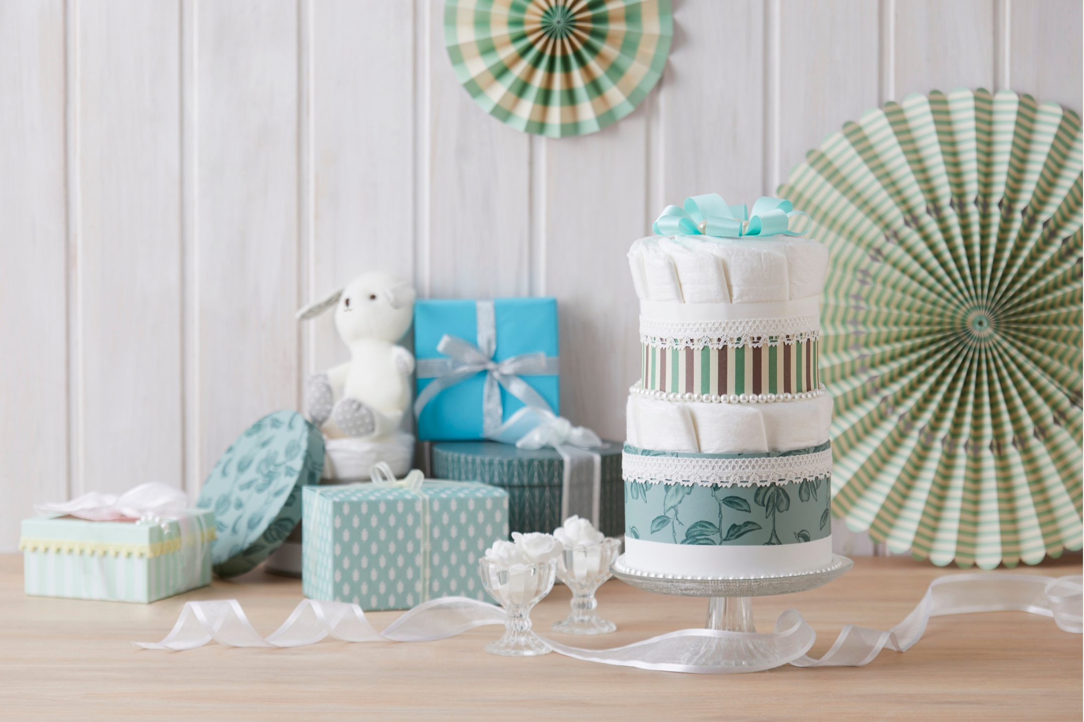 Decorative setup with a diaper cake, gifts, and party decorations on a wooden surface.